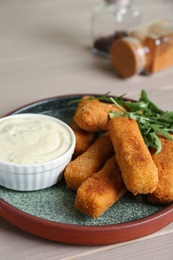 Photo of Plate of cheese sticks and sauce on table