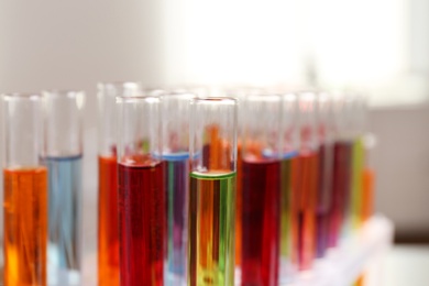 Photo of Test tubes with color liquids in rack, closeup. Solution chemistry