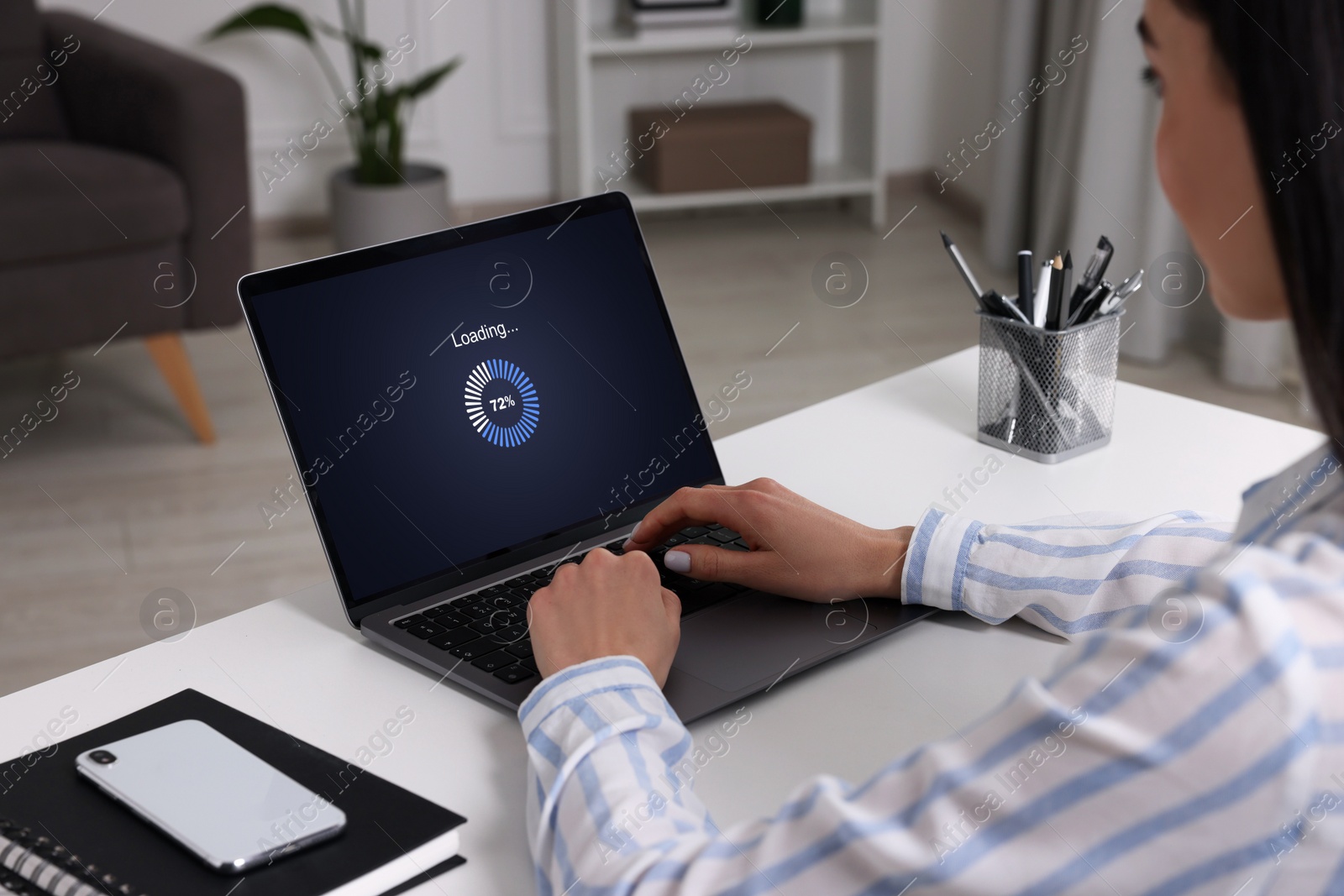 Image of Loading screen displaying progress. Woman working on laptop at table indoors, closeup