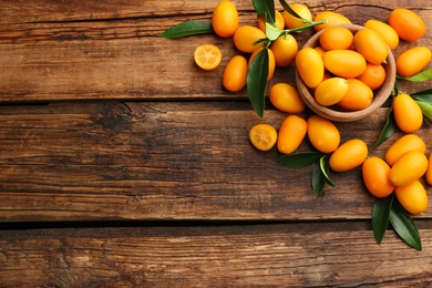 Fresh ripe kumquats on wooden table, flat lay. Space for text