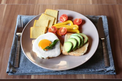 Tasty toasts with fried egg, avocado, cheese and vegetables served on wooden table