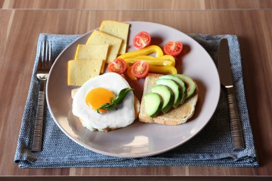 Photo of Tasty toasts with fried egg, avocado, cheese and vegetables served on wooden table