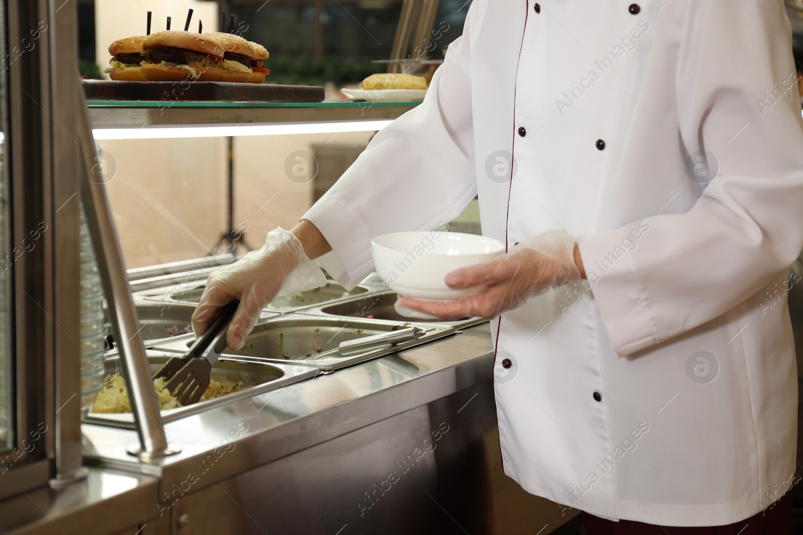 Photo of School canteen worker at serving line, closeup. Tasty food