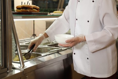 Photo of School canteen worker at serving line, closeup. Tasty food