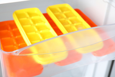 Photo of Different plastic ice cube trays in fridge