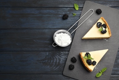 Photo of Pieces of delicious cheesecake with blackberries on dark wooden background, flat lay. Space for text