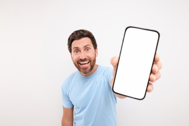 Photo of Handsome man showing smartphone in hand on white background