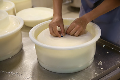 Photo of Worker decorating fresh cheese at modern factory, closeup