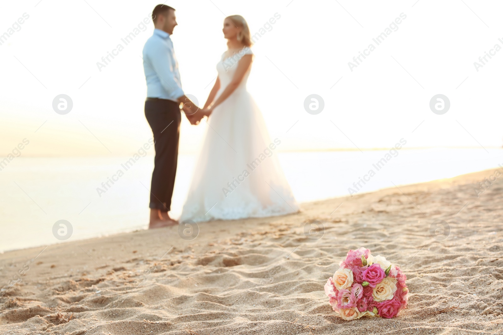 Photo of Bouquet and wedding couple on beach. Space for text