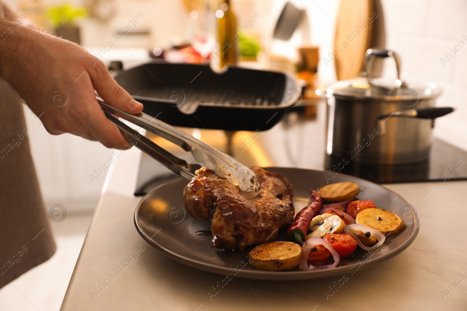 Photo of Man putting meat into plate with vegetables cooked on frying pan, closeup