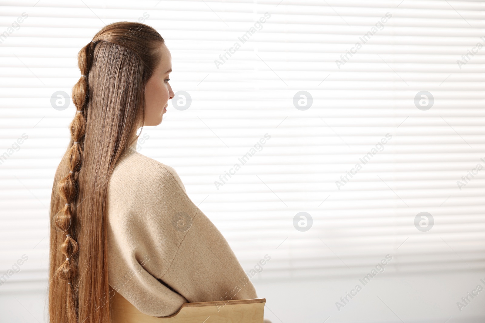 Photo of Young woman with long braided hair indoors, space for text