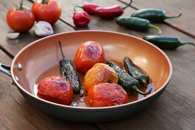 Photo of Frying pan with ingredients for salsa sauce on wooden table