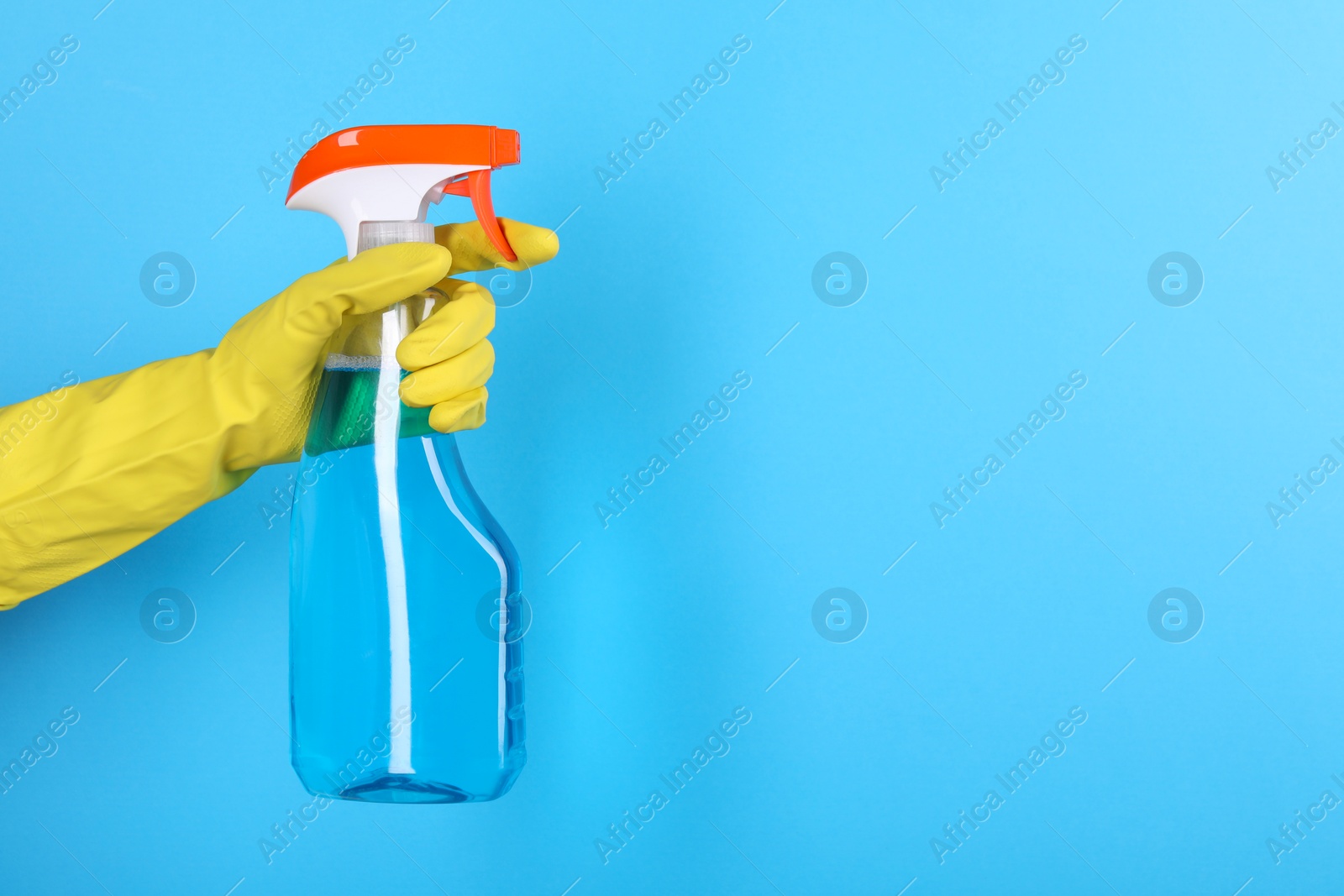 Photo of Woman holding plastic spray bottle on light blue background, closeup. Space for text