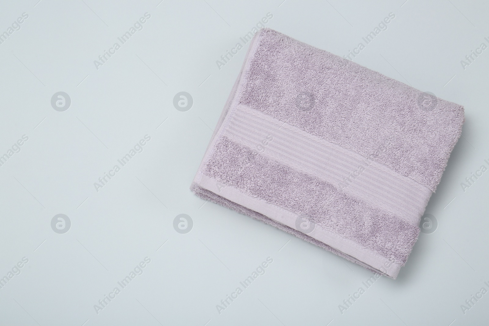 Photo of Violet terry towel on light grey background, top view. Space for text