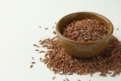 Caraway (Persian cumin) seeds and bowl on white table, space for text