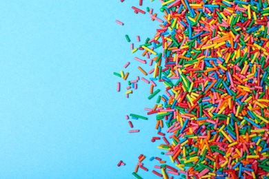 Photo of Colorful sprinkles on light blue background, flat lay with space for text. Confectionery decor