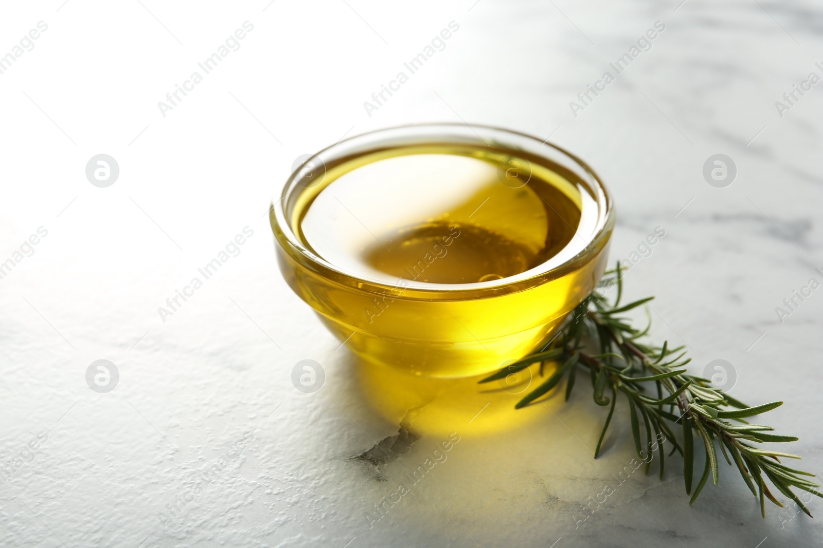 Photo of Bowl of rosemary oil on marble background