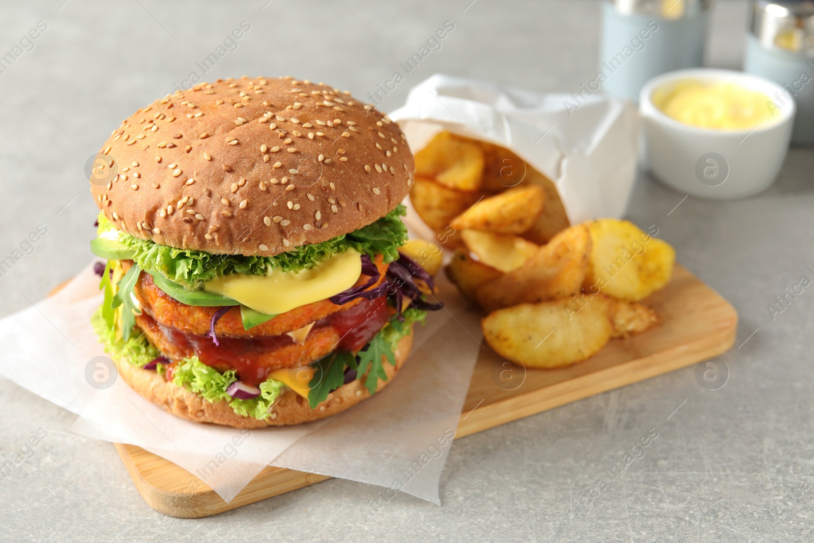 Photo of Vegan burger with carrot patties and fried potato served on grey table