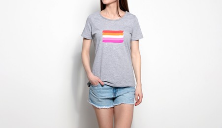 Image of Young woman wearing grey t-shirt with lesbian flag on white background. LGBT concept