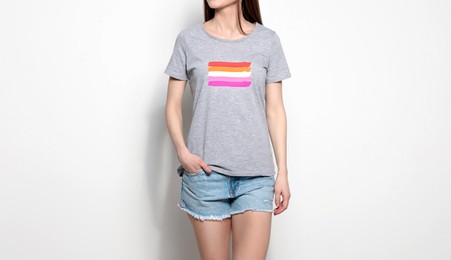 Young woman wearing grey t-shirt with lesbian flag on white background. LGBT concept