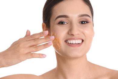 Photo of Young woman applying natural scrub on her face against white background