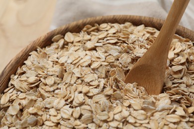 Photo of Wooden bowl and spoon with oatmeal on table, closeup