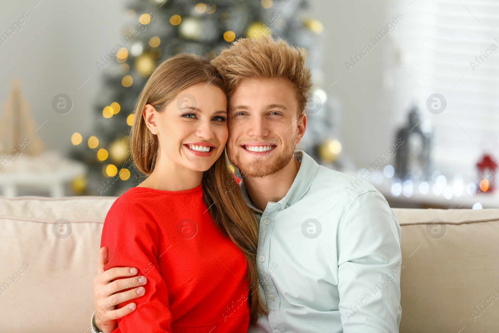 Photo of Happy young couple on sofa at home. Christmas celebration