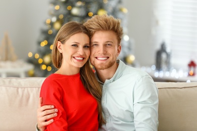 Photo of Happy young couple on sofa at home. Christmas celebration