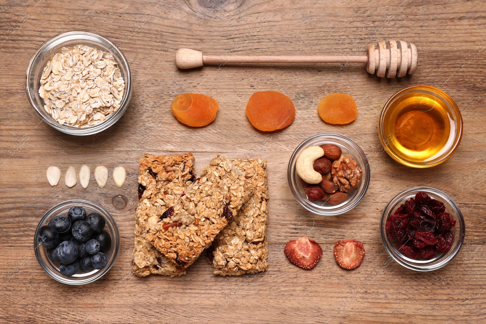 Photo of Tasty granola bars served on wooden table, flat lay