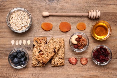 Photo of Tasty granola bars served on wooden table, flat lay