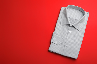 Photo of Male stylish grey shirt on red background, top view. Space for text