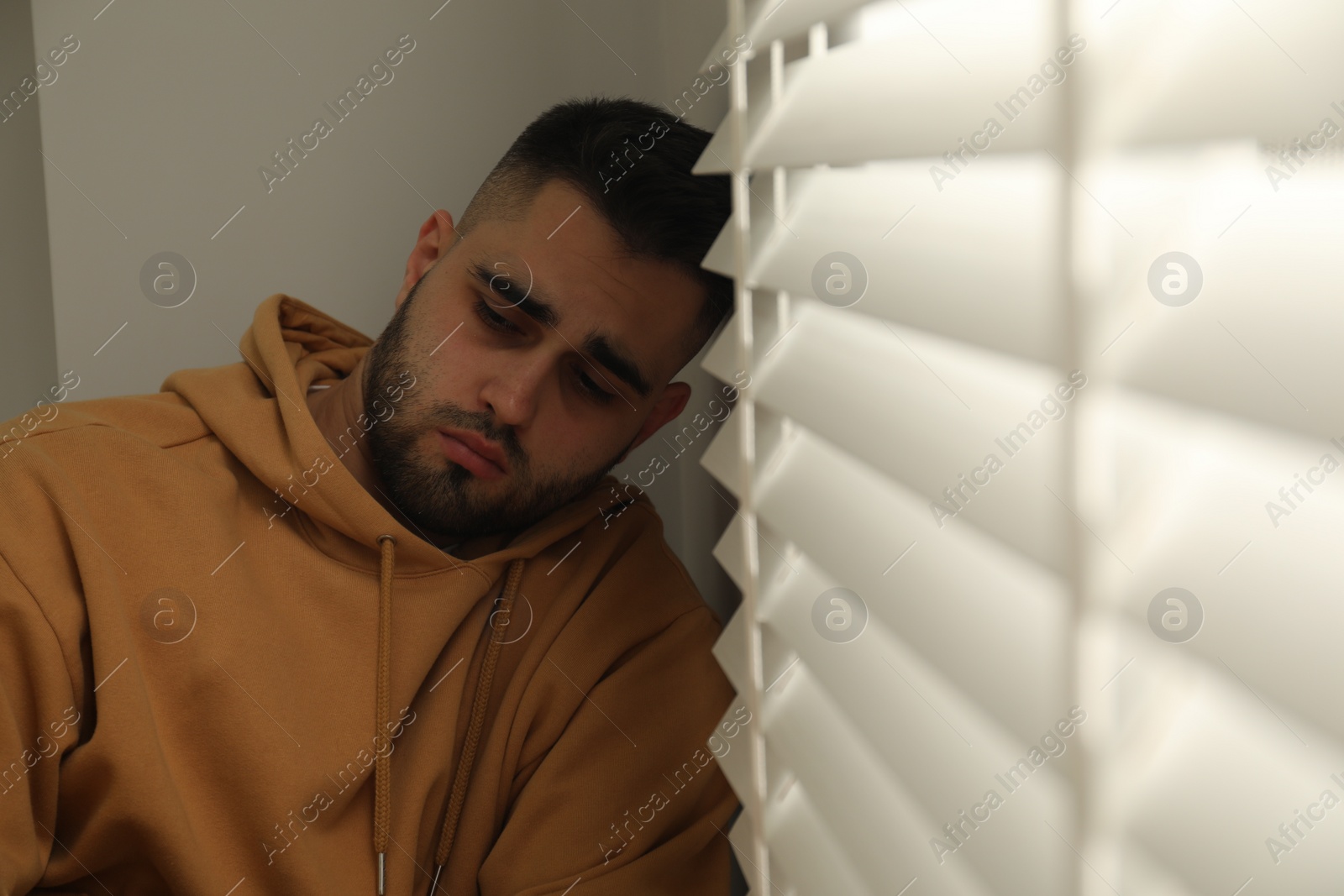 Photo of Sad young man and sitting near window