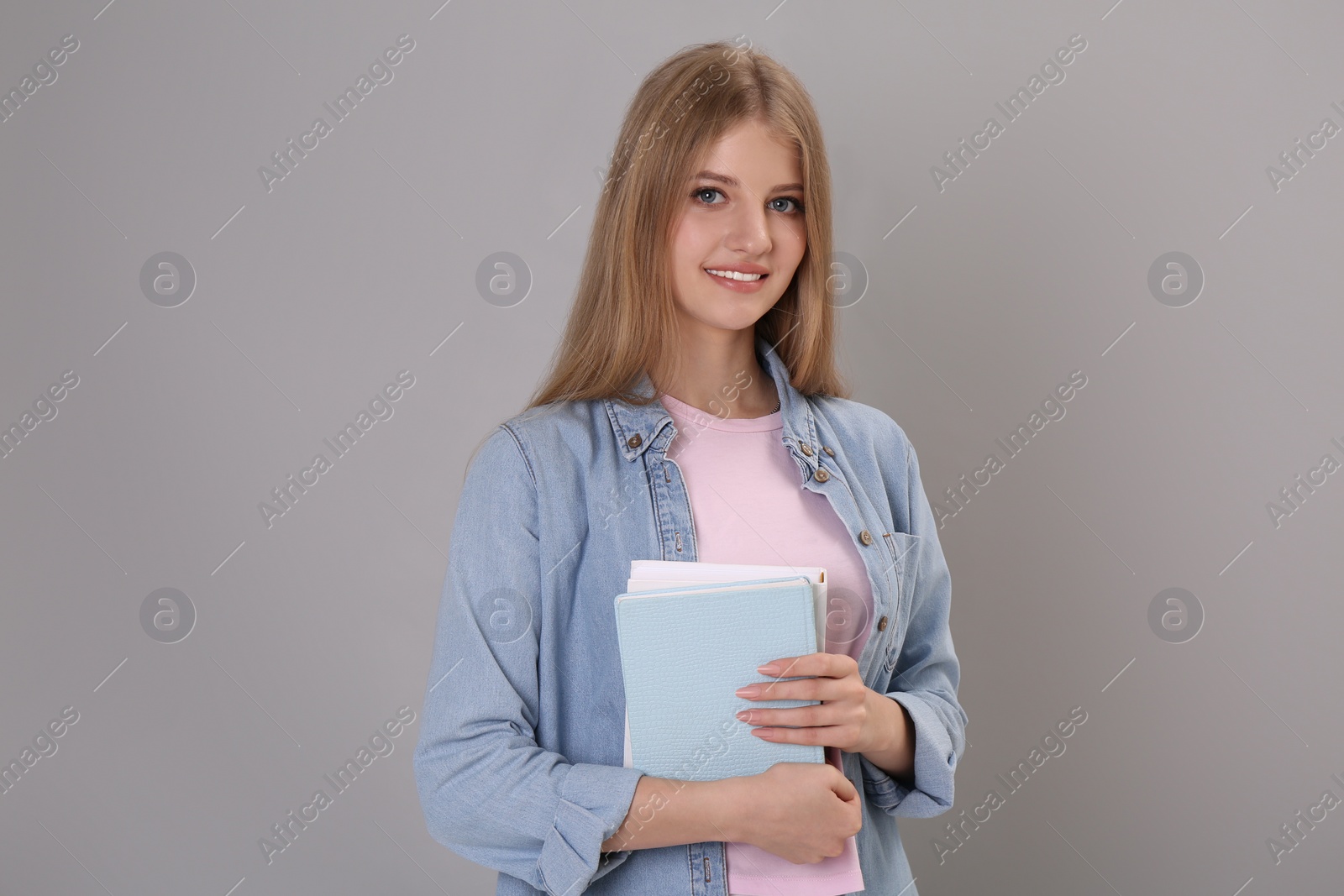 Photo of Teenage student holding books on grey background