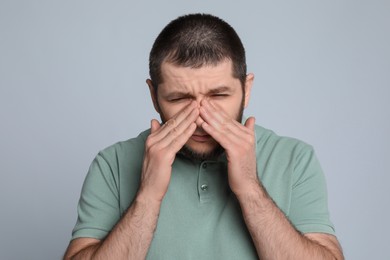 Man suffering from headache on light grey background