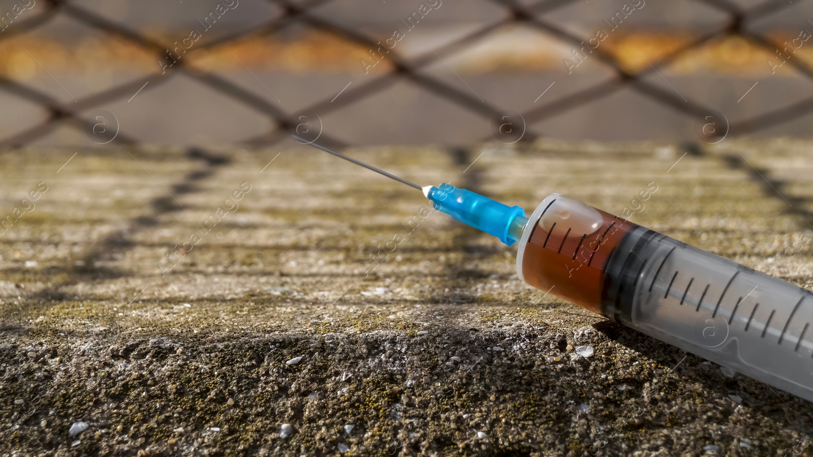 Photo of Syringe with hard drugs on stone surface outdoors, closeup. Space for text