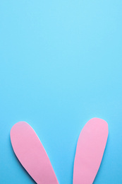 Photo of Top view of paper bunny ears on blue background, space for text. Easter celebration