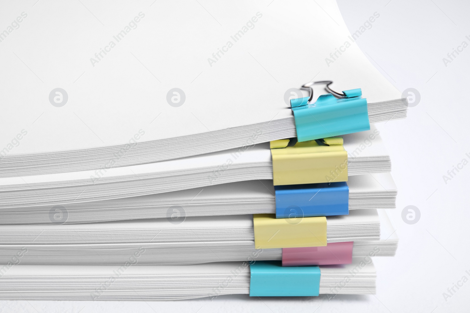 Photo of Many sheets of paper with colorful clips on white background, closeup