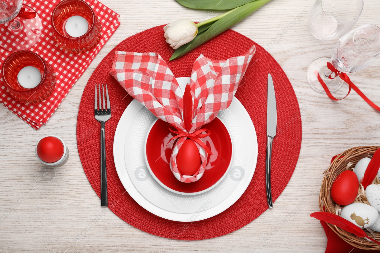 Photo of Festive table setting with bunny ears made of red egg and napkin, flat lay Easter celebration