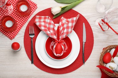 Festive table setting with bunny ears made of red egg and napkin, flat lay Easter celebration