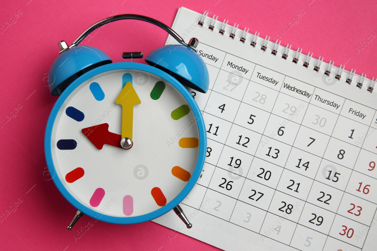 Photo of Alarm clock and calendar on pink background, flat lay. Reminder concept