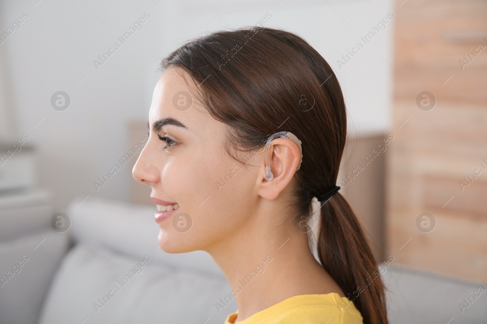 Photo of Young woman with hearing aid at home
