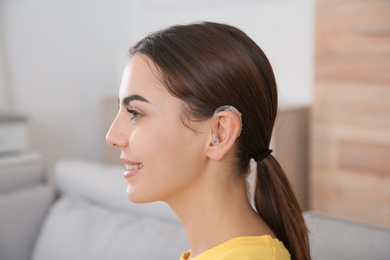 Photo of Young woman with hearing aid at home