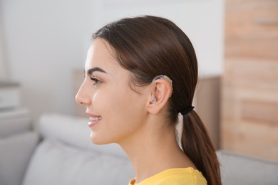 Young woman with hearing aid at home