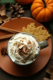 Photo of Flat lay composition of tasty pumpkin spice latte with whipped cream in cup on wooden table