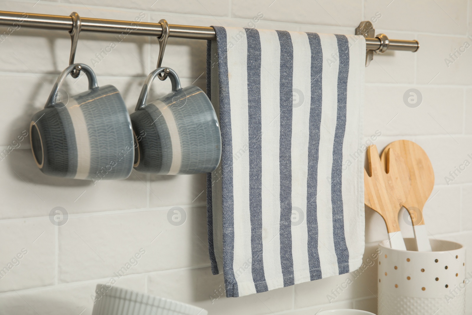 Photo of Kitchen towel and cups hanging on rack indoors