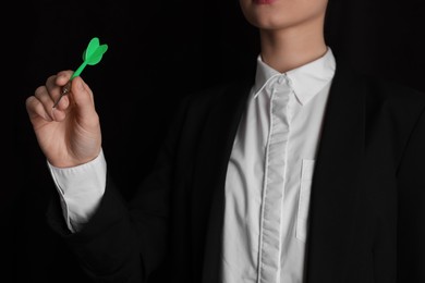 Photo of Businesswoman holding green dart on black background, closeup