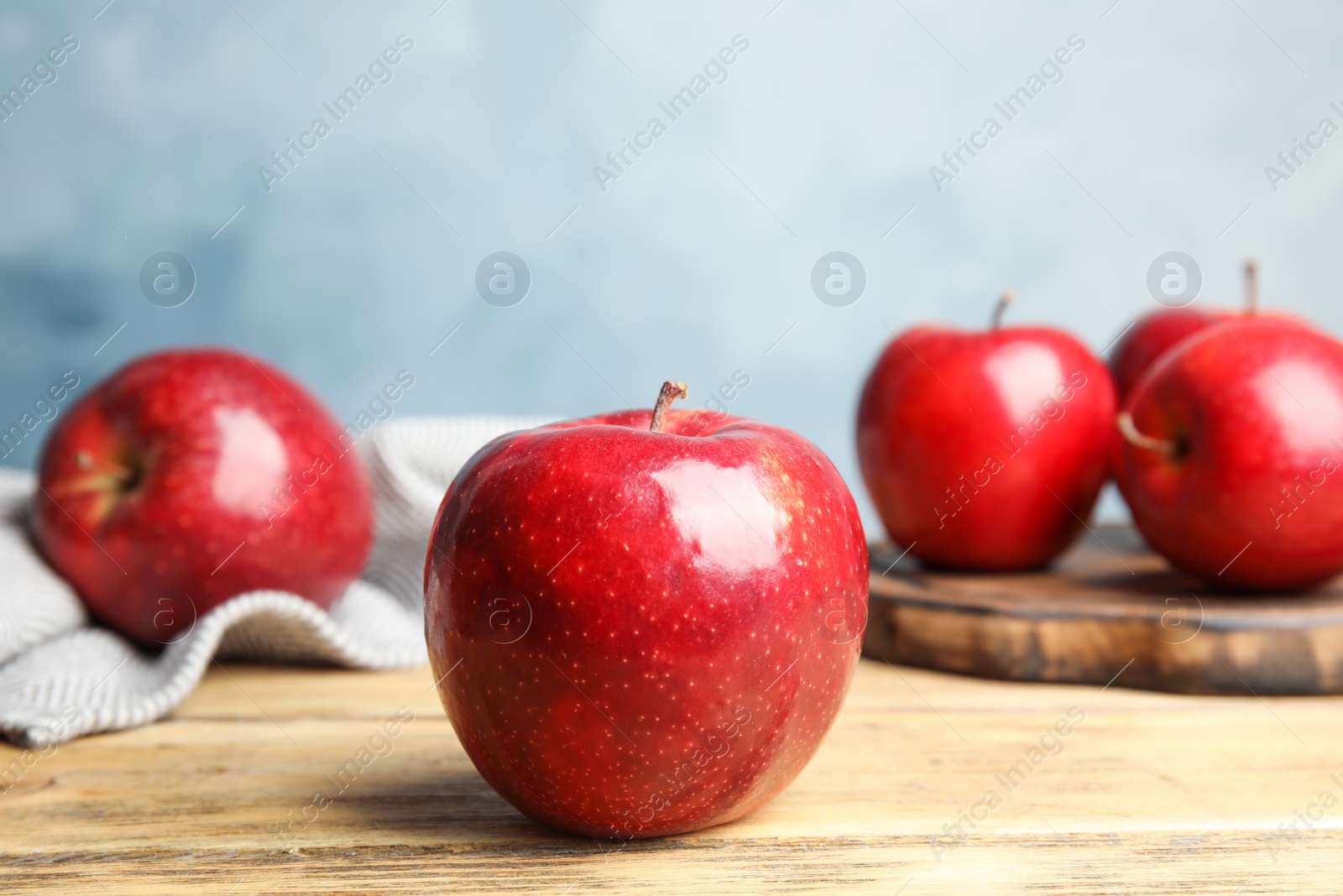 Photo of Ripe juicy red apples on wooden table against blue background