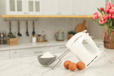 Photo of Modern mixer, eggs and bowl with flour on white marble table in kitchen, space for text