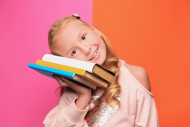 Photo of Cute little girl with books on colorful background