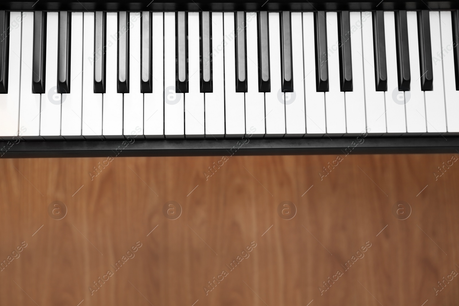 Photo of Modern piano with black and white keys over floor, top view. Space for text